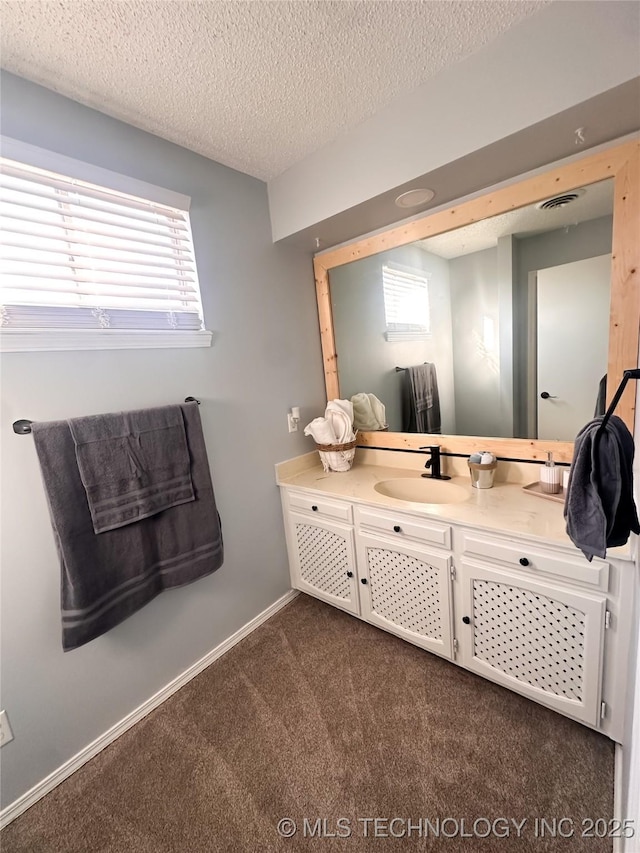 bathroom featuring visible vents, baseboards, a textured ceiling, and vanity