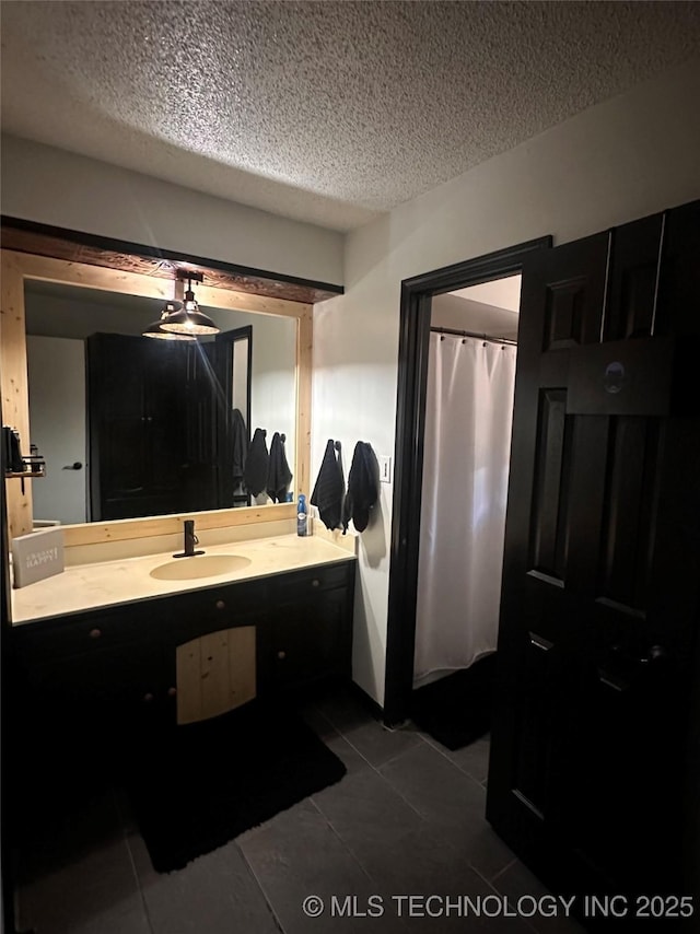 bathroom with tile patterned flooring, a textured ceiling, and vanity