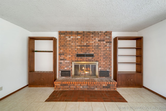 unfurnished living room featuring a fireplace, light tile patterned floors, and a textured ceiling