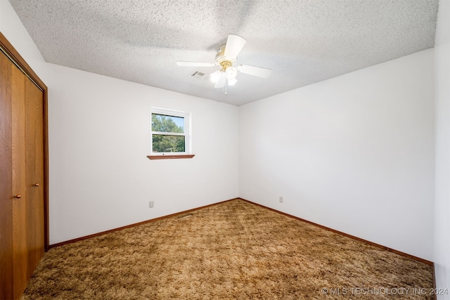 empty room with carpet, ceiling fan, and a textured ceiling