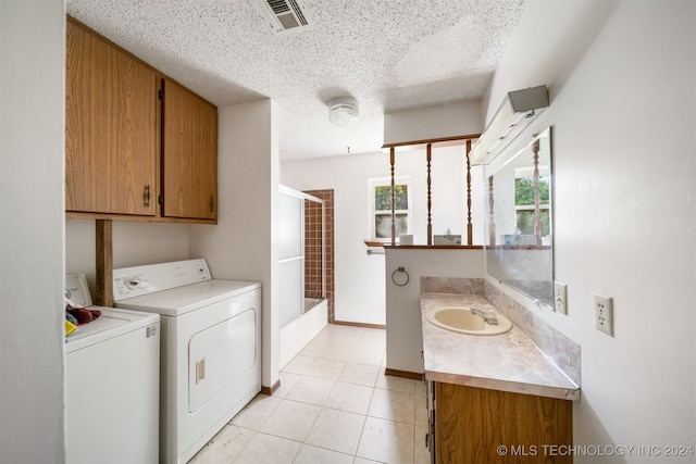 laundry area with sink, light tile patterned floors, a textured ceiling, and washing machine and clothes dryer