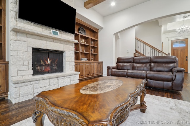 living room with a stone fireplace, dark hardwood / wood-style flooring, beamed ceiling, and a notable chandelier