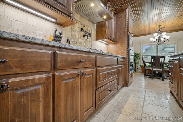 kitchen featuring light stone countertops, a chandelier, decorative light fixtures, wood ceiling, and custom exhaust hood