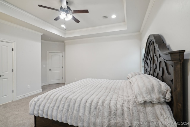 carpeted bedroom with a raised ceiling, ceiling fan, and crown molding