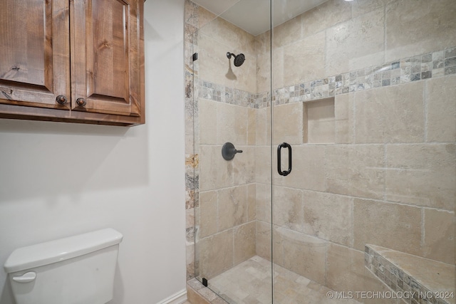 bathroom featuring toilet and a shower with shower door