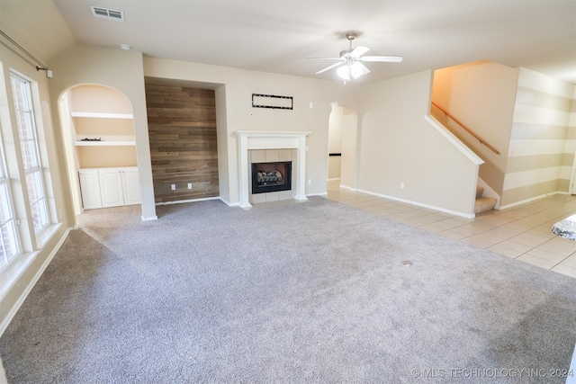 unfurnished living room featuring ceiling fan, a healthy amount of sunlight, light tile patterned floors, and a tiled fireplace