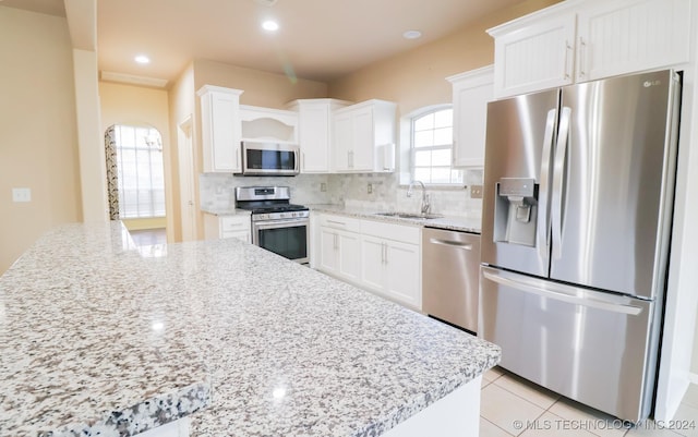 kitchen featuring white cabinetry, sink, light stone counters, and appliances with stainless steel finishes