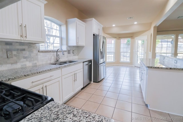 kitchen featuring white cabinetry, sink, light stone counters, decorative backsplash, and appliances with stainless steel finishes