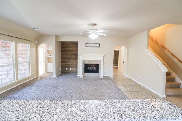 unfurnished living room featuring ceiling fan, light tile patterned floors, and a fireplace