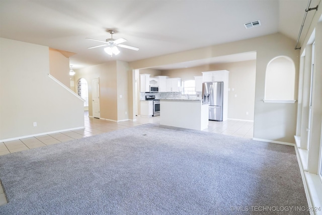 unfurnished living room with ceiling fan, light tile patterned floors, and vaulted ceiling