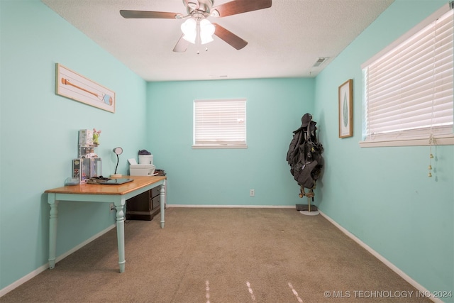 office area featuring a textured ceiling, ceiling fan, and light carpet