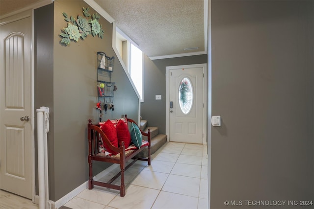 tiled entryway with a textured ceiling and ornamental molding