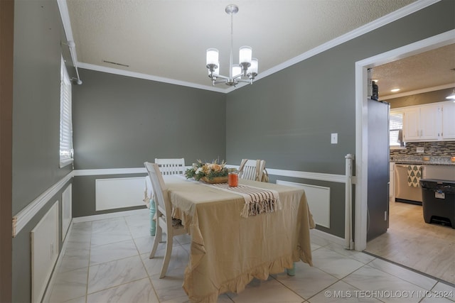 dining area featuring light wood-type flooring, a textured ceiling, ornamental molding, and a notable chandelier