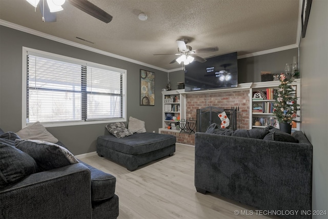 living room featuring light hardwood / wood-style flooring, ceiling fan, ornamental molding, a fireplace, and a textured ceiling