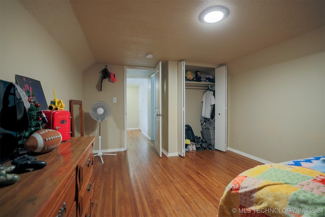 bedroom featuring vaulted ceiling, a closet, a textured ceiling, and light wood-type flooring