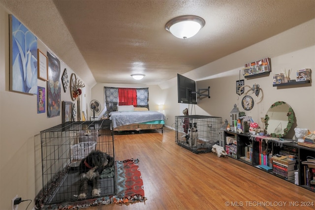 bedroom with hardwood / wood-style floors, a textured ceiling, and vaulted ceiling