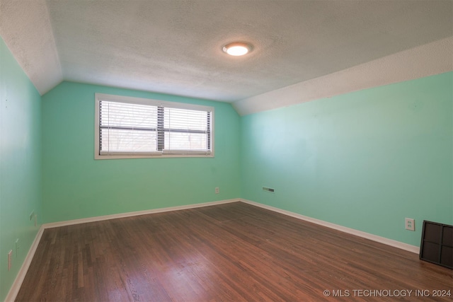 additional living space featuring a textured ceiling, dark hardwood / wood-style flooring, and lofted ceiling