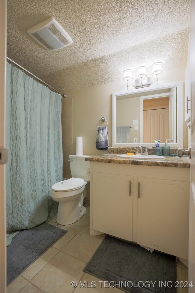 bathroom with a shower with shower curtain, tile patterned floors, vanity, a textured ceiling, and toilet