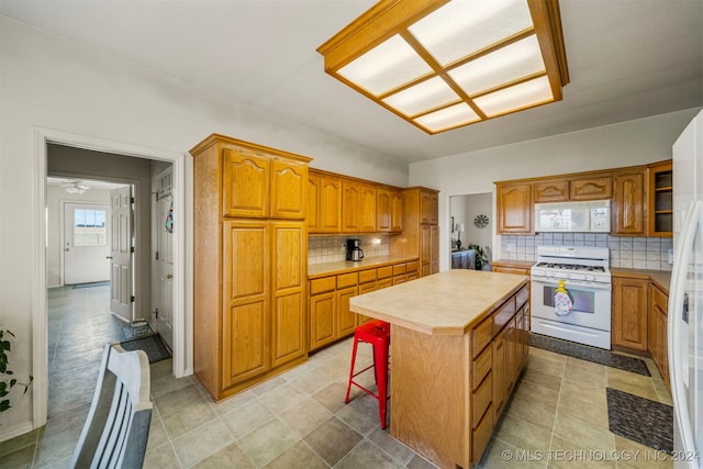 kitchen with a breakfast bar, a center island, decorative backsplash, and white appliances