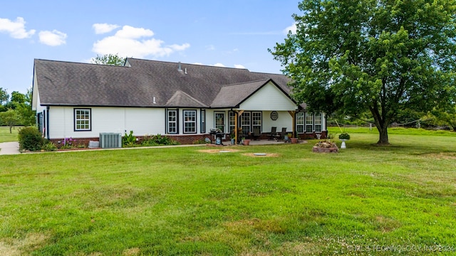 back of property with a yard and central AC