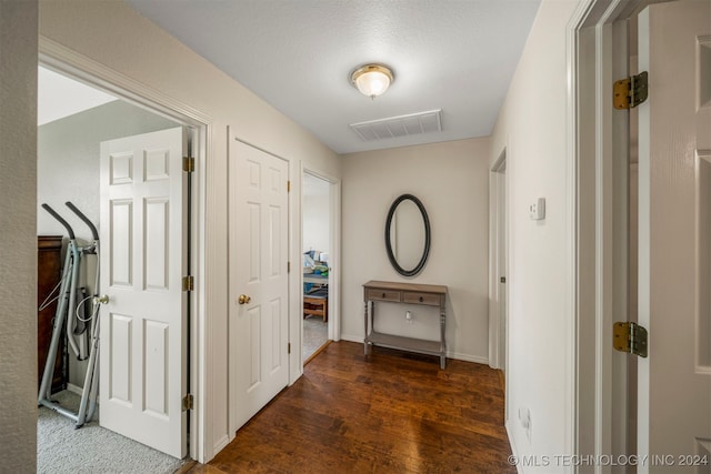 corridor with a textured ceiling and dark hardwood / wood-style flooring