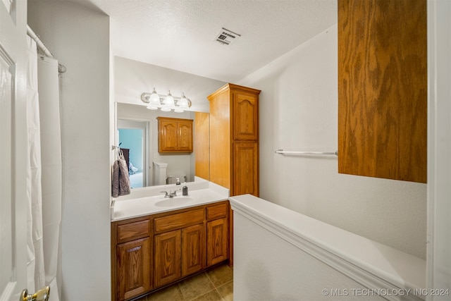 bathroom with vanity, a textured ceiling, and toilet