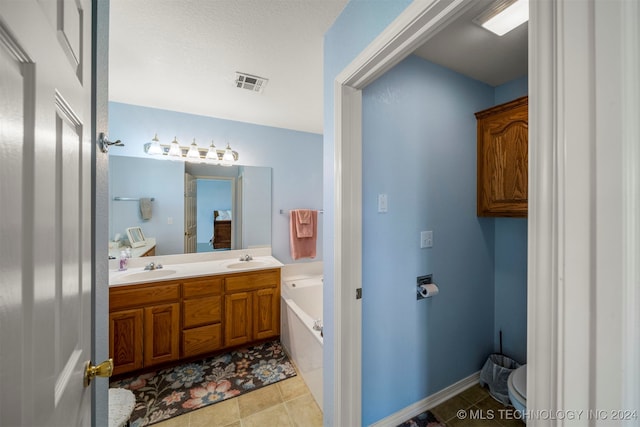 bathroom with tile patterned floors, a tub, vanity, and toilet