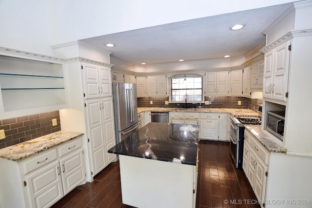 kitchen with white cabinets, high end appliances, light stone countertops, and crown molding