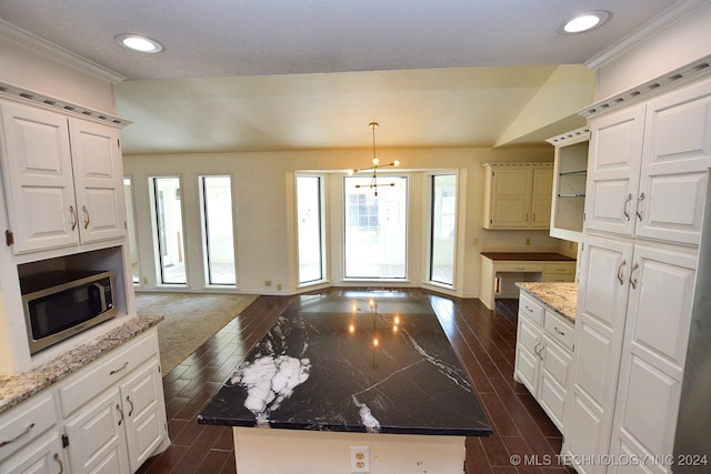 kitchen featuring white cabinetry, dark hardwood / wood-style flooring, dark stone counters, decorative light fixtures, and a kitchen island