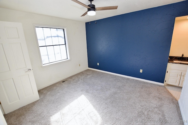 unfurnished bedroom featuring light carpet, ceiling fan, and sink