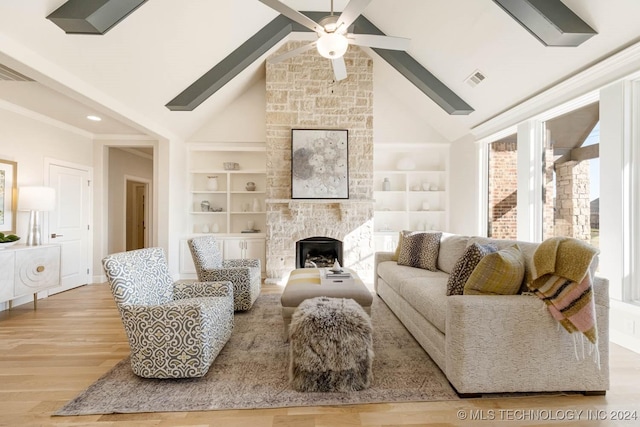 living room featuring high vaulted ceiling, a stone fireplace, ceiling fan, built in shelves, and light hardwood / wood-style floors