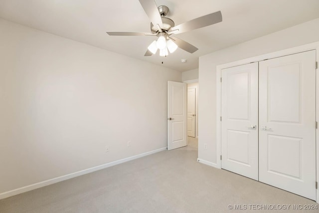 unfurnished bedroom featuring ceiling fan, a closet, and light carpet