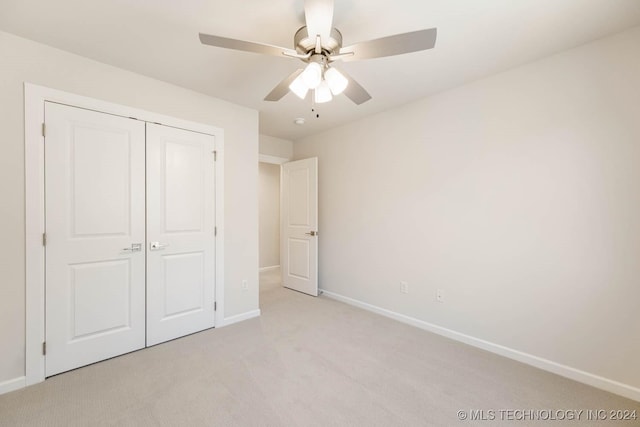 unfurnished bedroom with ceiling fan, light colored carpet, and a closet