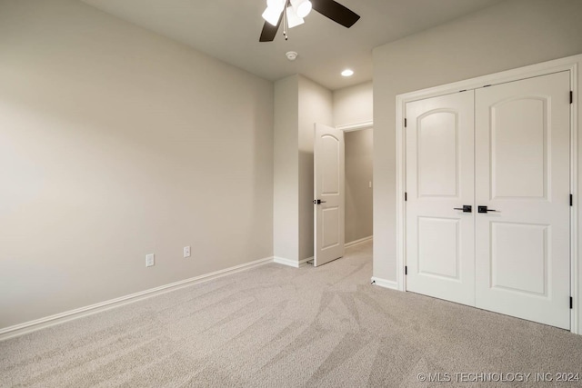 unfurnished bedroom featuring ceiling fan, light carpet, and a closet