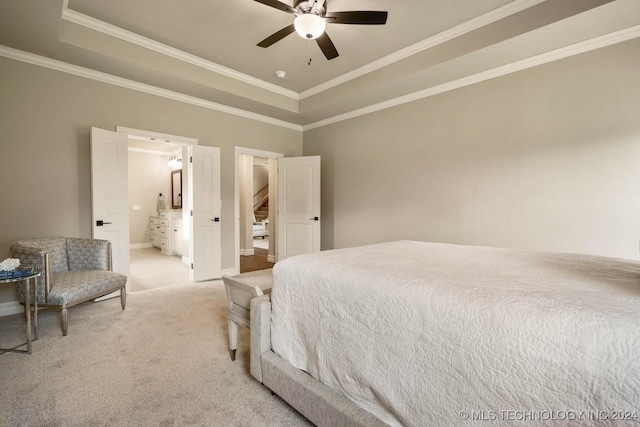 bedroom with light carpet, ceiling fan, ornamental molding, connected bathroom, and a tray ceiling