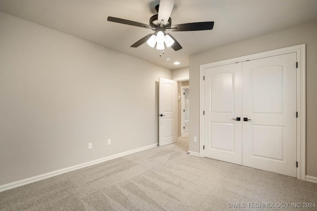 unfurnished bedroom with ceiling fan, light colored carpet, and a closet