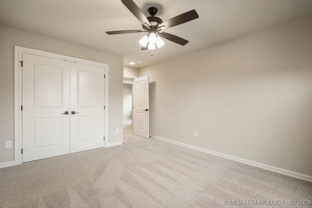 unfurnished bedroom with ceiling fan, light carpet, and a closet