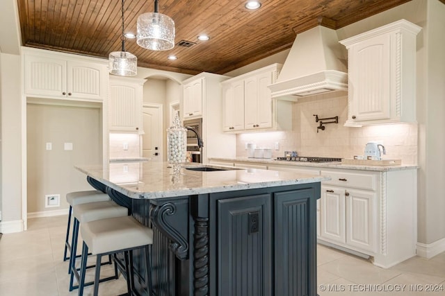 kitchen with a kitchen island with sink, white cabinets, wood ceiling, and custom exhaust hood