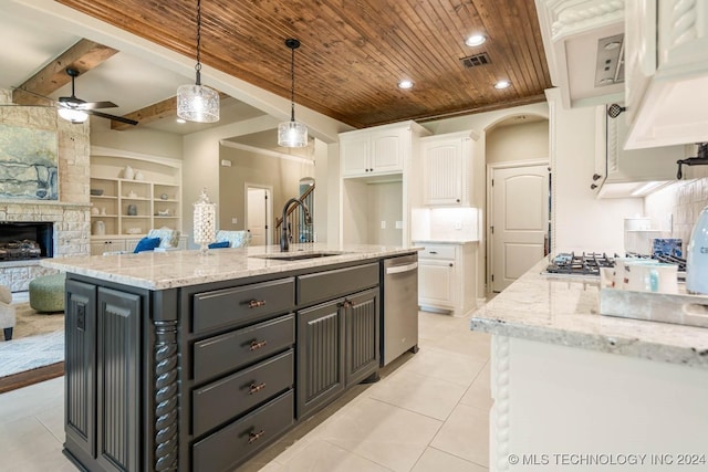 kitchen with built in shelves, a kitchen island with sink, sink, pendant lighting, and white cabinets