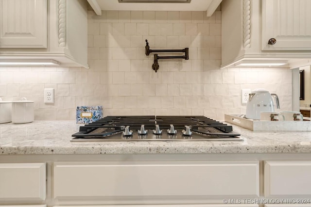 kitchen with decorative backsplash, light stone counters, and stainless steel gas cooktop