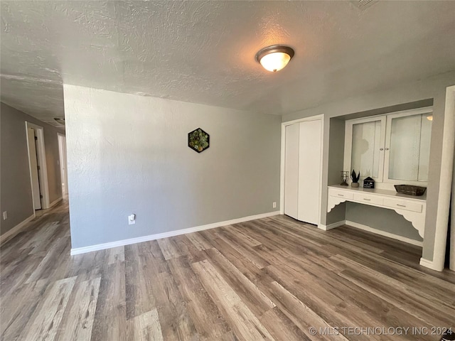 unfurnished room featuring wood-type flooring and a textured ceiling