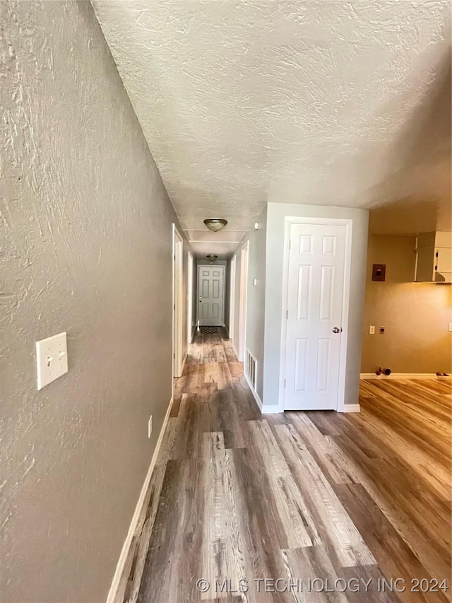 hall with hardwood / wood-style floors and a textured ceiling