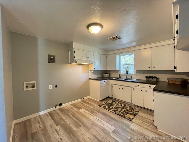 kitchen with a textured ceiling, light wood-type flooring, white cabinetry, and sink