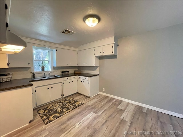 kitchen with white cabinets, light wood-type flooring, and sink