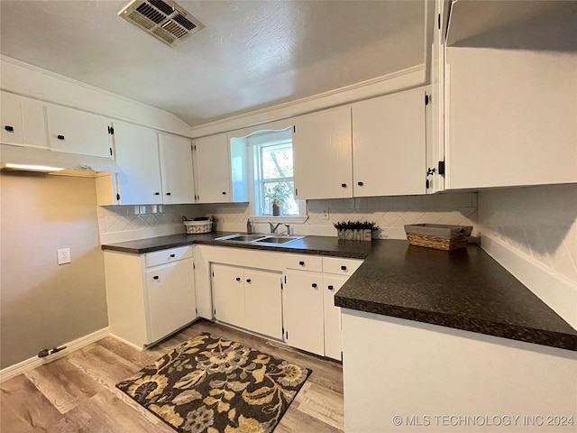 kitchen featuring light hardwood / wood-style floors, white cabinetry, sink, and tasteful backsplash