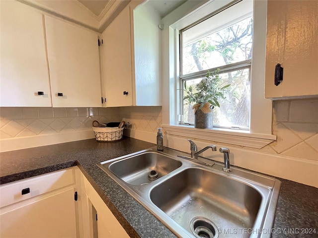 kitchen featuring white cabinets, backsplash, and sink