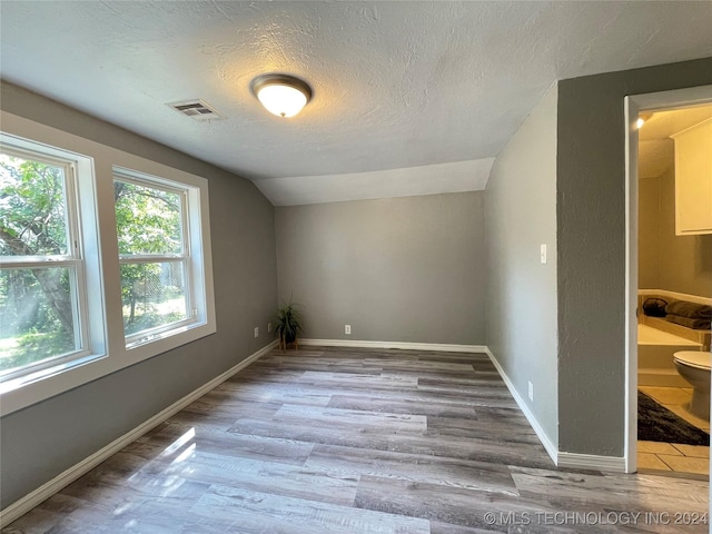 bonus room featuring a textured ceiling, light hardwood / wood-style floors, and lofted ceiling