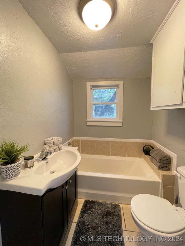 bathroom featuring tile patterned floors, vanity, a textured ceiling, vaulted ceiling, and a tub