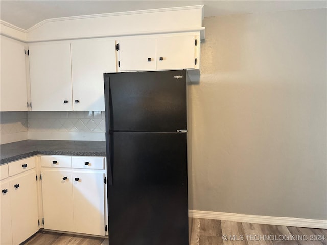 kitchen with dark hardwood / wood-style flooring, backsplash, black fridge, crown molding, and white cabinets