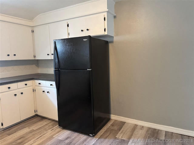 kitchen with black refrigerator, decorative backsplash, crown molding, light hardwood / wood-style flooring, and white cabinets